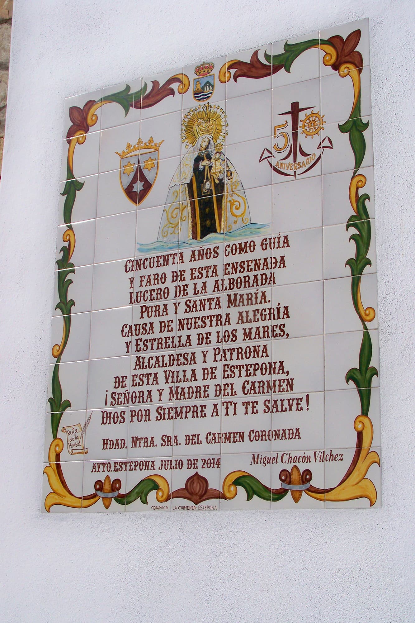 Azulejo de cerámica pintado con versos en una fachada blanca de Estepona