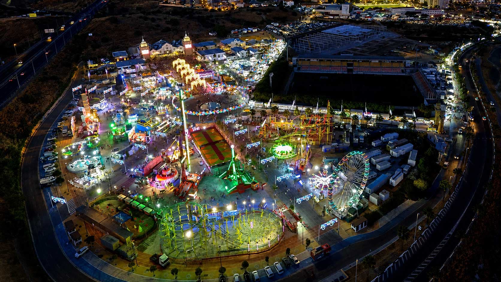 Vista aérea nocturna del Recinto Ferial de Estepona durante la Feria Mayor, con las atracciones iluminadas