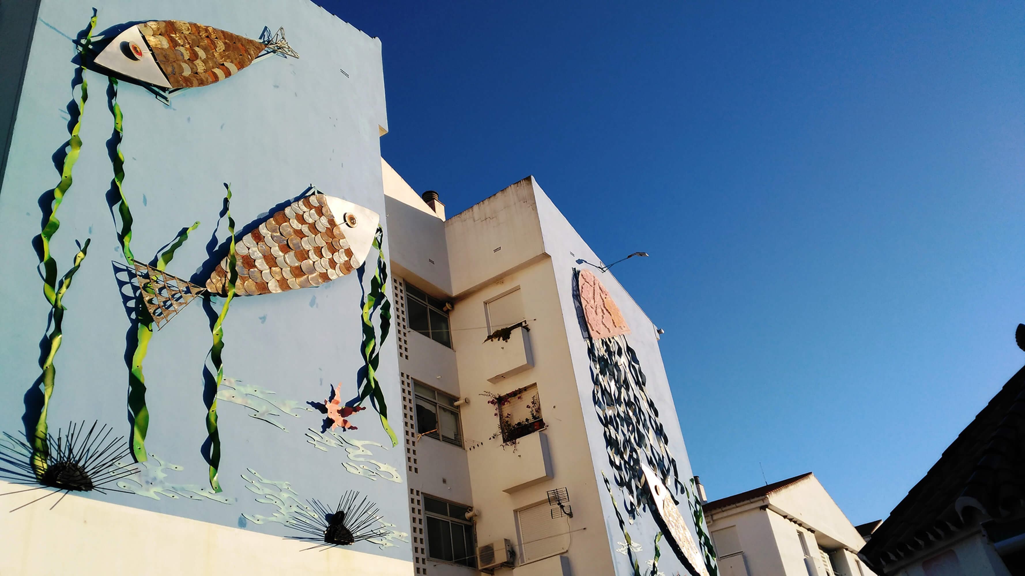 Mural de gran formato con peces pintado sobre la medianera de un edificio de Estepona