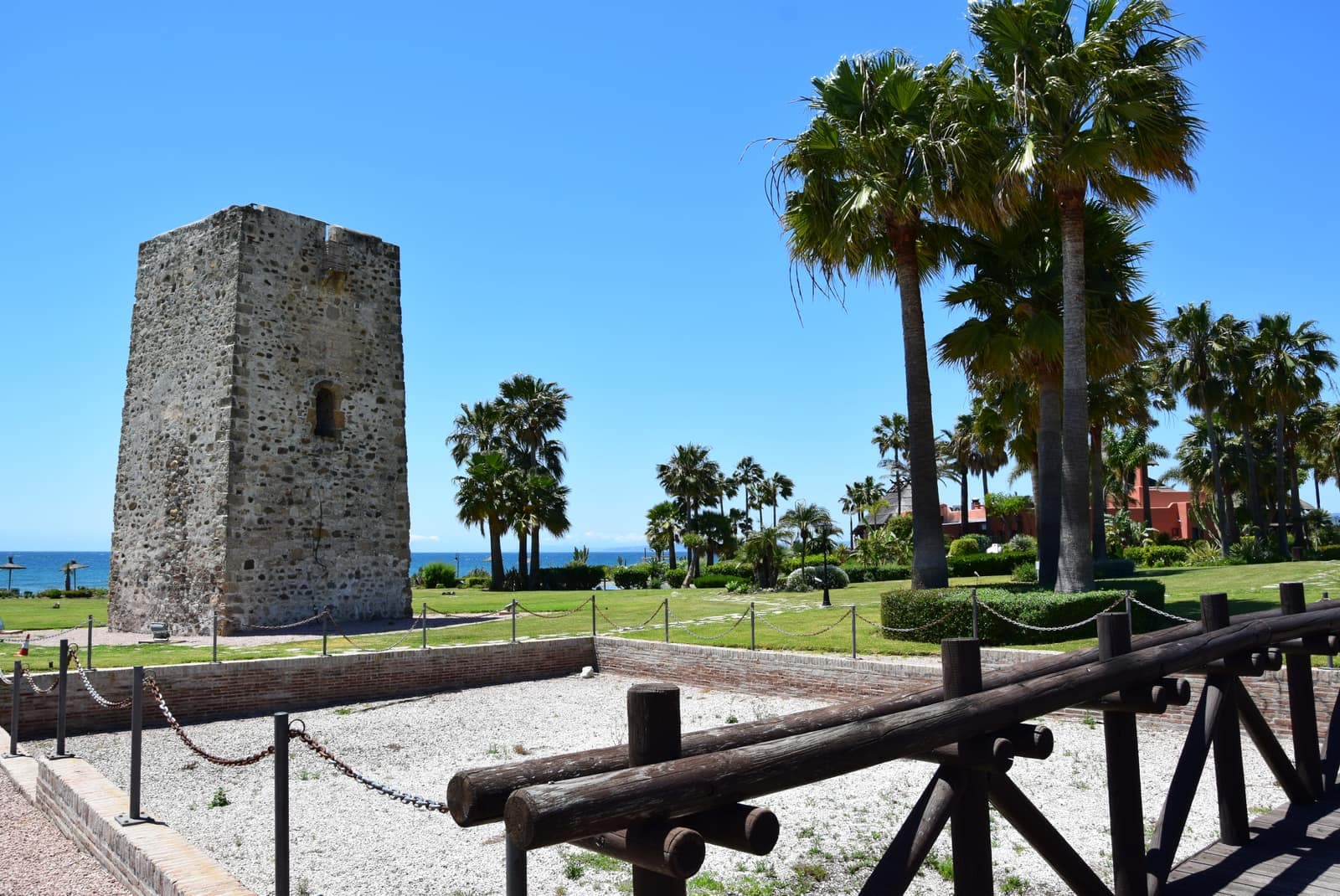 Torre almenara de Guadalmansa o Desmochada, la única de planta cuadrada, junto al mar y rodeada de palmeras
