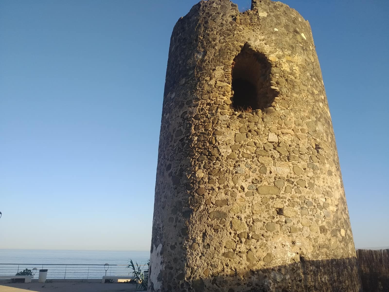 Torre almenara del Velerín vista desde abajo, con el hueco de la puerta elevada y el Mediterráneo al fondo