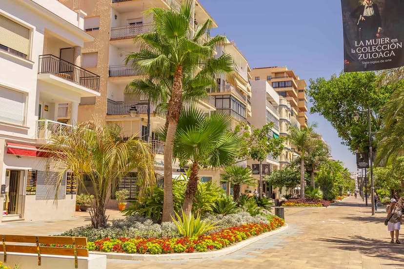 Bulevar de Estepona con jardines en flor y pancarta de la exposición Zuloaga.