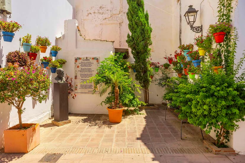 Rincón del casco de Estepona con busto, macetas y placa poética.