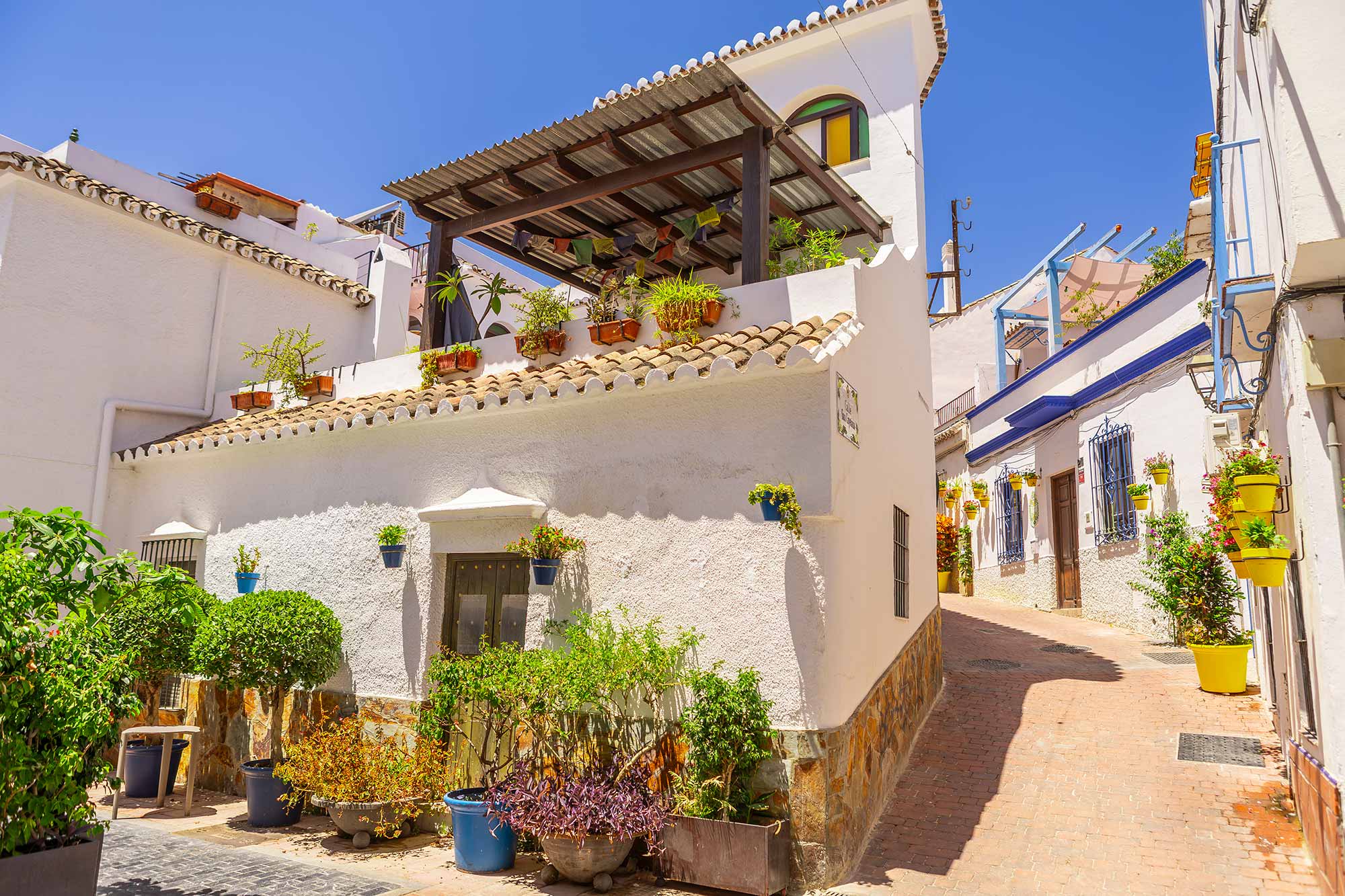 Calle típica del casco de Estepona con fachadas blancas y macetas.